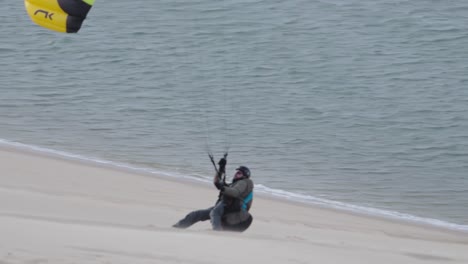 Male-paraglider-paragliding-on-Dune-du-Pilat-in-France,-landing-view,-ocean-background