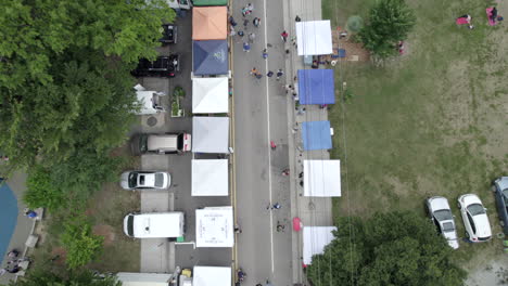 Aerial-drone-farmers-market,-vendors-selling-to-customers,-tents