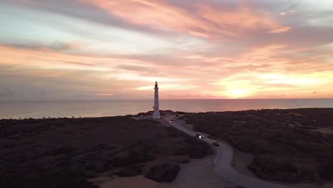 Drone-shot-of-California-light-house-in-Aruba,-Caribbean-with-spectacular-sunset-circulating-structure