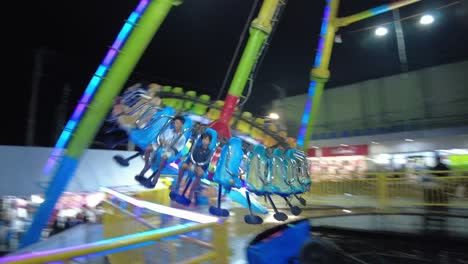A-dynamic-shot-of-a-spinning-disc-ride-in-an-amusement-park-which-spins-the-passengers-around-while-it-continuously-swings-from-left-to-right
