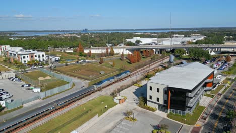 Drone-shot-of-an-Amtrak-train-leaving-a-station-in-Lakeland,-central-Florida,-on-its-way-to-Tampa-on-a-sunny-day