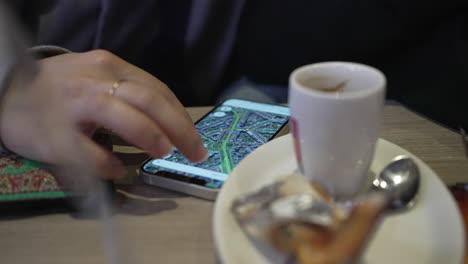 Close-up-Detail-of-woman-using-Google-Maps-on-phone-at-cafe-place