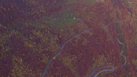 Hairpin-mountain-road-leading-up-steep-slope-with-colored-forest-in-autumn-season