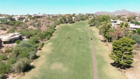 Wide-aerial-of-a-dry-fairway-with-large-mansions-surrounding-it-in-Phoenix