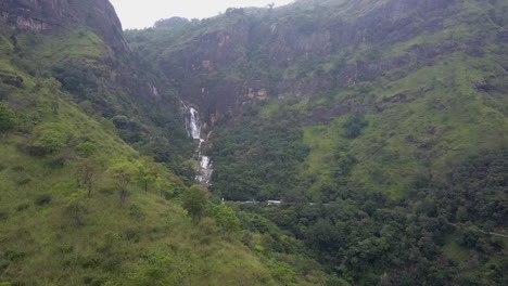 Slow-aerial-flight-to-multi-tier-waterfall,-Sri-Lanka-mountain-jungle