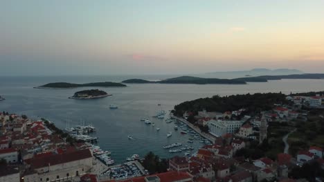 Drone-shot-of-a-seaside-town-in-Croatia-with-the-sun-setting-out-over-the-water