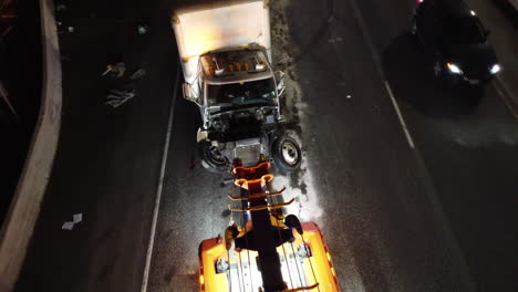 Crashed-cargo-truck-getting-help-from-emergency-vehicle,-aerial-view