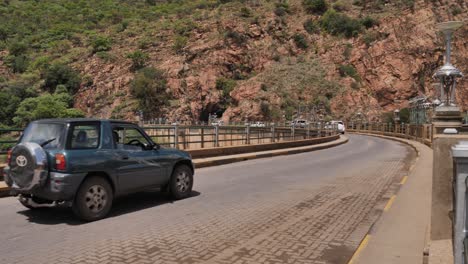 Vehicle-traffic-drives-across-curved-top-of-Hartbeespoort-hydro-Dam