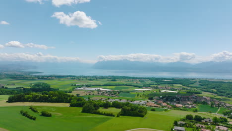 Vista-Panorámica-Aérea-Sobre-El-Campo-Cerca-Del-Pueblo-De-Yens-Con-Vistas-Al-Lago-Leman-En-Vaud,-Suiza