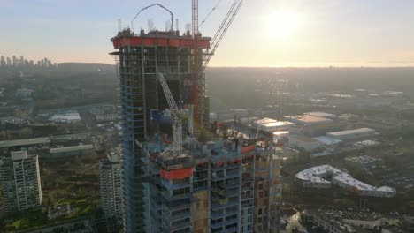 Development-Site-Of-Tall-Apartment-Buildings-With-Cranes-At-Work-On-The-Rooftop-At-Sunset-In-Burnaby,-British-Columbia,-Canada