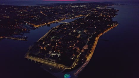 City-street-lights-illuminating-dark-town-Zadar-at-night,-aerial