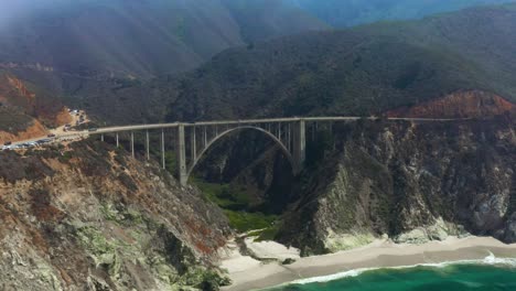 Cars-Traveling-on-Big-Sur's-Bixby-Creek-Bridge,-California---Aerial-Drone