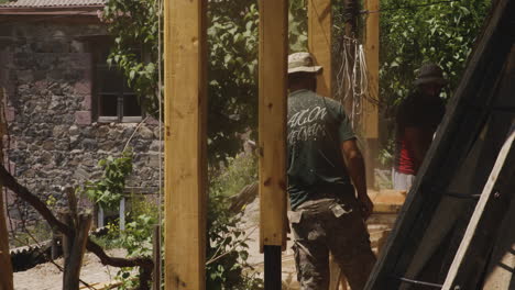 Two-workers-building-house-terrace-with-wooden-pillars-in-Georgia