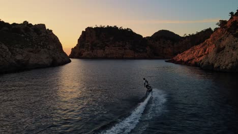 A-surfer-is-surfing-in-the-sea-at-the-golden-hour-of-Punta-Galera-IBIZA,-Spain
