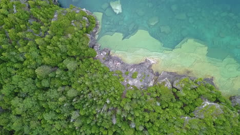 Aerial-descends-to-rocky-cliff,-clear-water-of-Georgian-Bay-Lake-Huron