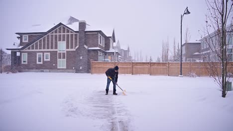 Man-working-at-cleaning-snow-from-driveway-in-winter-after-a-snow-storm