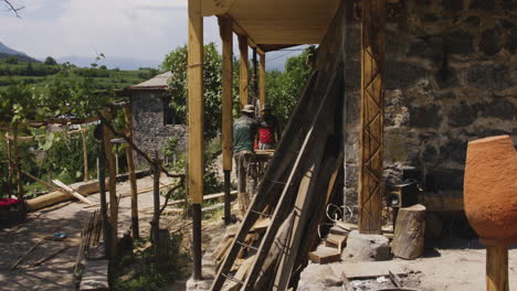 Two-Carpenters-Working-on-Traditional-Georgian-House,-Chobareti-Georgia,-Pan