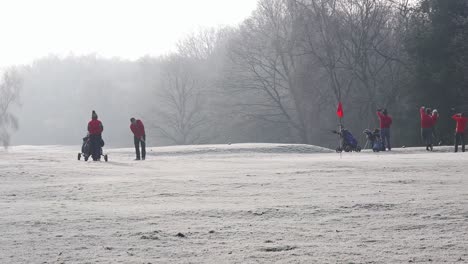 London,-England---January-22-2023:-Golfers-putting-on-a-frost-covered-golf-green-in-winter