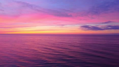 Calm-sea-water-and-vivid-colors-sunset,-aerial-drone-descend-view