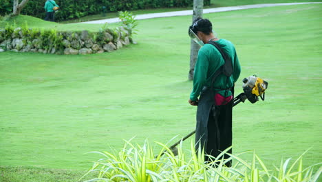 Asian-Worker-Trimming-Grass-With-Grass-Cutter-At-The-Garden-Of-A-Luxury-Hotel-In-The-Philippines