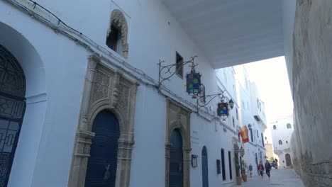 Pan-Down-From-Street-Ceiling-With-Blue-Tricycle-Approaching-And-Driving-Past-In-Tangier,-Medina