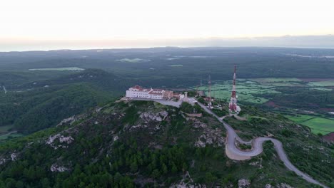 Aerial-footage-flying-over-telecommunication-tower-on-Monte-Toro,-Menorca's-biggest-mountain-peak-with-road-to-the-lookout