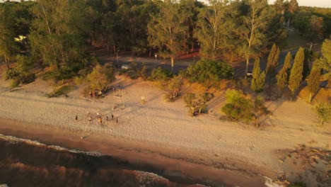 Orbitaufnahme-Einer-Mannschaft,-Die-Bei-Sonnenuntergang-An-Der-Küste-Von-Fray-Bentos-Beachvolleyball-Spielt,-Uruguay