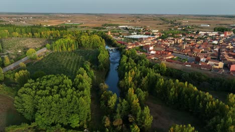 Flying-over-the-Rio-Esla-river-of-Mansilla-De-Las-Mules,-Leon,-Spain-at-sunset