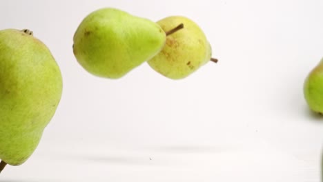 Whole-pears-bouncing-and-rolling-onto-white-studio-backdrop-in-4k-slow-motion