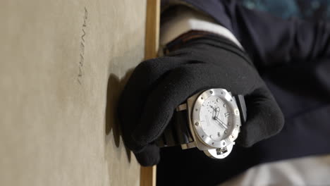 VERTICAL-Salesman-displaying-luxurious-Panerai-maritime-model-wristwatch-close-up-to-customer-in-designer-boutique