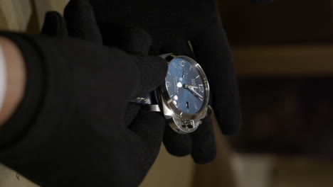 Person-with-gloves-inspecting-luxury-wristwatch,-close-up-view