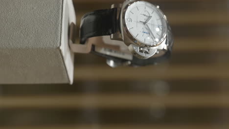 VERTICAL-Expensive-Panerai-silver-nautical-wristwatch-in-designer-boutique-retail-display-case,-Close-up-panning-shot