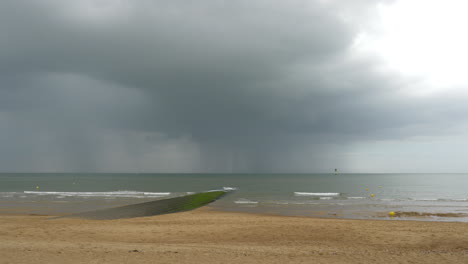 Distant-Rain-and-Thunderstorm-over-the-Sea,-Beach-and-Breakwater-View