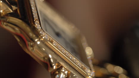 VERTICAL-Sparkling-elegant-gold-Cartier-wristwatch-dial-detail-turning-slow-motion-in-the-light