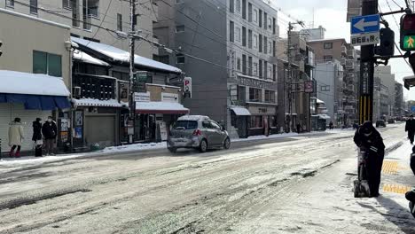 Dos-Trabajadores-Masculinos,-Paleando-Nieve-En-La-Calle-En-Kyoto,-Japón