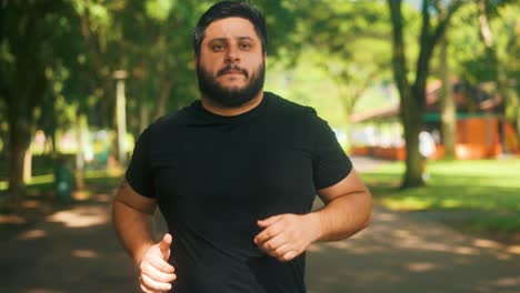Young-overweight-man-jogging-at-the-park-on-a-sunny-summer-day-in-slow-motion