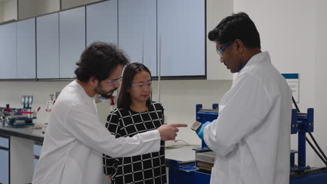 A-Male-Scientist-Holding-A-Piece-Of-Tile-Explaining-To-Asian-Woman-And-Arab-Man