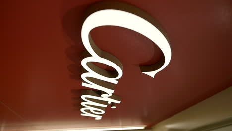 Vertical-video-of-Cartier-logo-sign-in-shopping-mall,-close-up,-slow-motion