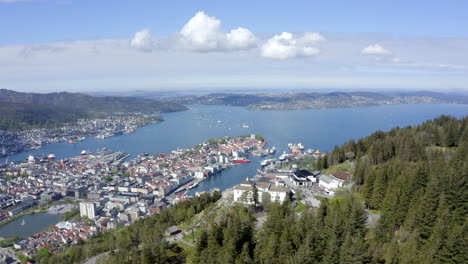 Beautiful-drone-shot-flying-over-the-restaurant-and-viewpoint-on-Mount-Fløyen,-revealing-the-gorgeous-city-of-Bergen-beneath-the-mountain