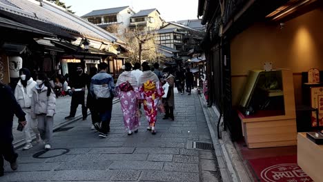 Dos-Mujeres-Asiáticas-Con-Kimonos-Caminan-Por-La-Calle-Comercial-Tradicional-En-Kyoto,-Japón