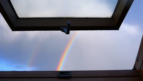 Schauen-Sie-Durch-Das-Fenster-Im-Dachboden-Auf-Den-Himmel-Mit-Wenigen-Wolken-Und-Regenbogen