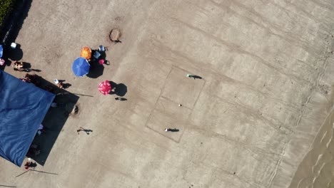 Rotating-bird's-eye-aerial-drone-shot-of-two-friends-playing-beach-soccer-with-a-field-drawn-in-the-sand-on-the-Bessa-Beach-in-the-coastal-capital-city-of-Joao-Pessoa,-Paraiba,-Brazil-on-a-summer-day