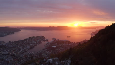 Beautiful-dramatic-sunset-over-Bergen,-Norway,-flying-over-a-mountain-ridge