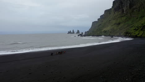 Aerial:-Flyover-group-of-tourists-riding-horses-on-the-beach-of-Vik-in-Iceland