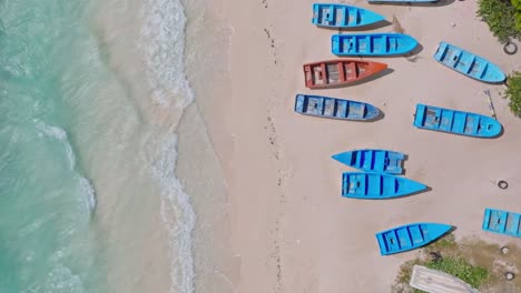 Aerial-top-down-flight-over-beautiful-sandy-beach-with-colorful-boats-and-crystal-clear-ocean-water-in-summer