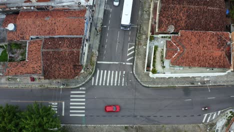 Descending-bird's-eye-shot-of-a-small-Brazilian-intersection-with-cars-and-motorcycles-driving-by-in-the-historic-downtown-of-the-coastal-capital-city-of-Joao-Pessoa,-Paraiba,-Brazil-during-sunset
