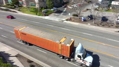 Schneider-National-Truck-With-Shipment-Moving-on-Interstate-Highway,-California-USA,-aerial-Tracking-Shot