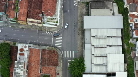 Top-bird's-eye-shot-of-a-small-Brazilian-intersection-with-cars-and-motorcycles-driving-by-in-the-historic-downtown-of-the-coastal-capital-city-of-Joao-Pessoa,-Paraiba,-Brazil-during-golden-hour