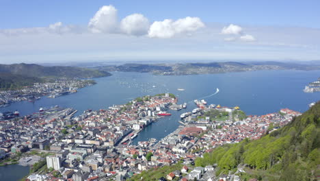 Beautiful-drone-shot-of-Bergen,-Norway,-pulling-back-from-the-city-and-over-the-mountain