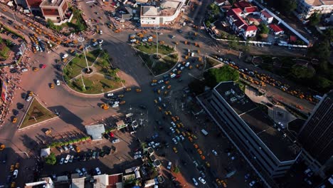 Aerial-tilt-view-of-traffic-in-a-roundabout-in-sunny-downtown-Yaounde,-Cameroon